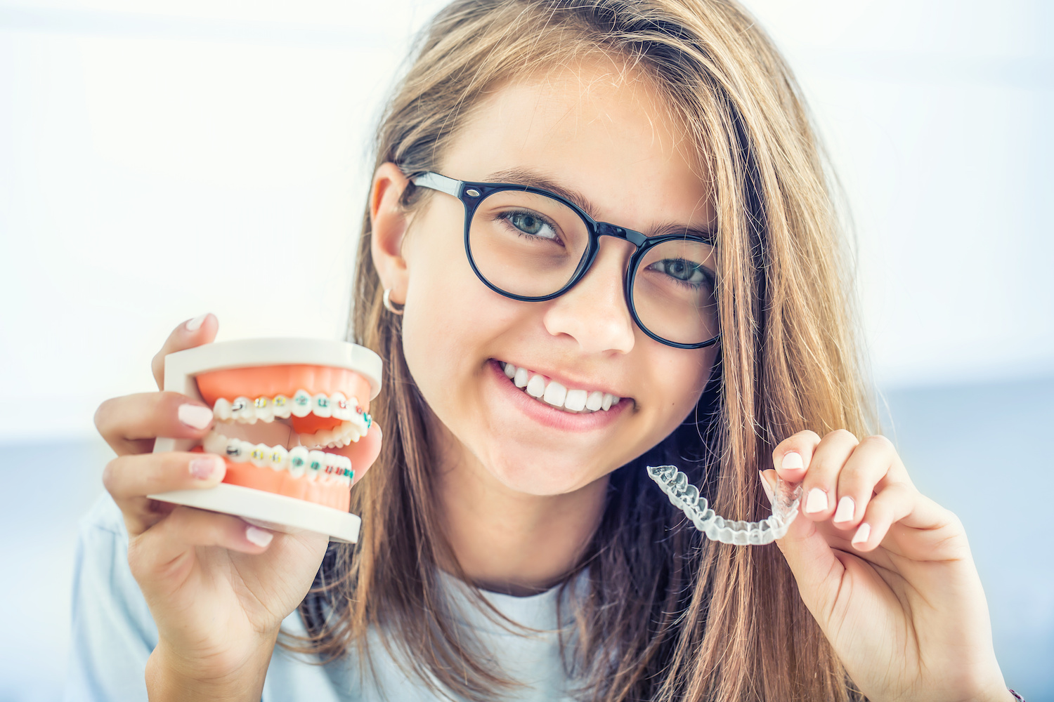 Dental invisible braces or silicone trainer in the hands of a young smiling girl. Orthodontic concept — Invisalign.